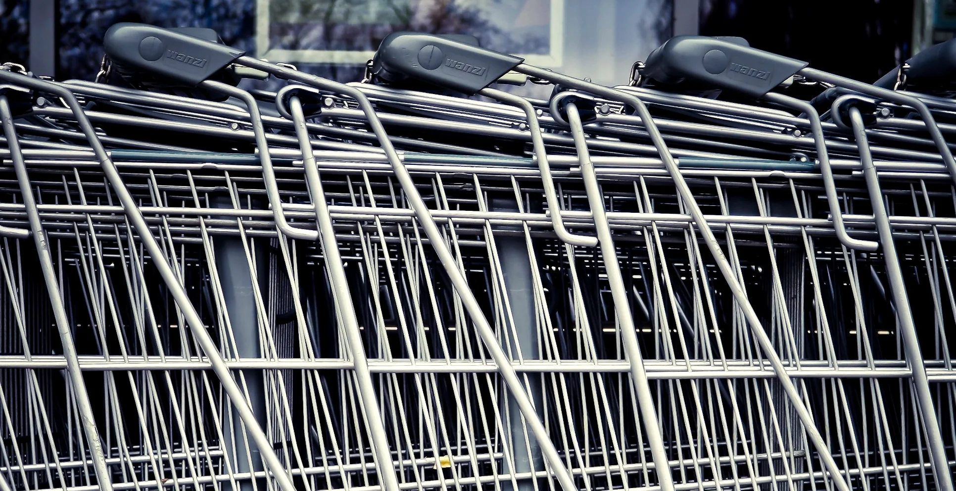 Three Wanzl trolleys nested together, showing nesting depth and the branded handle grips